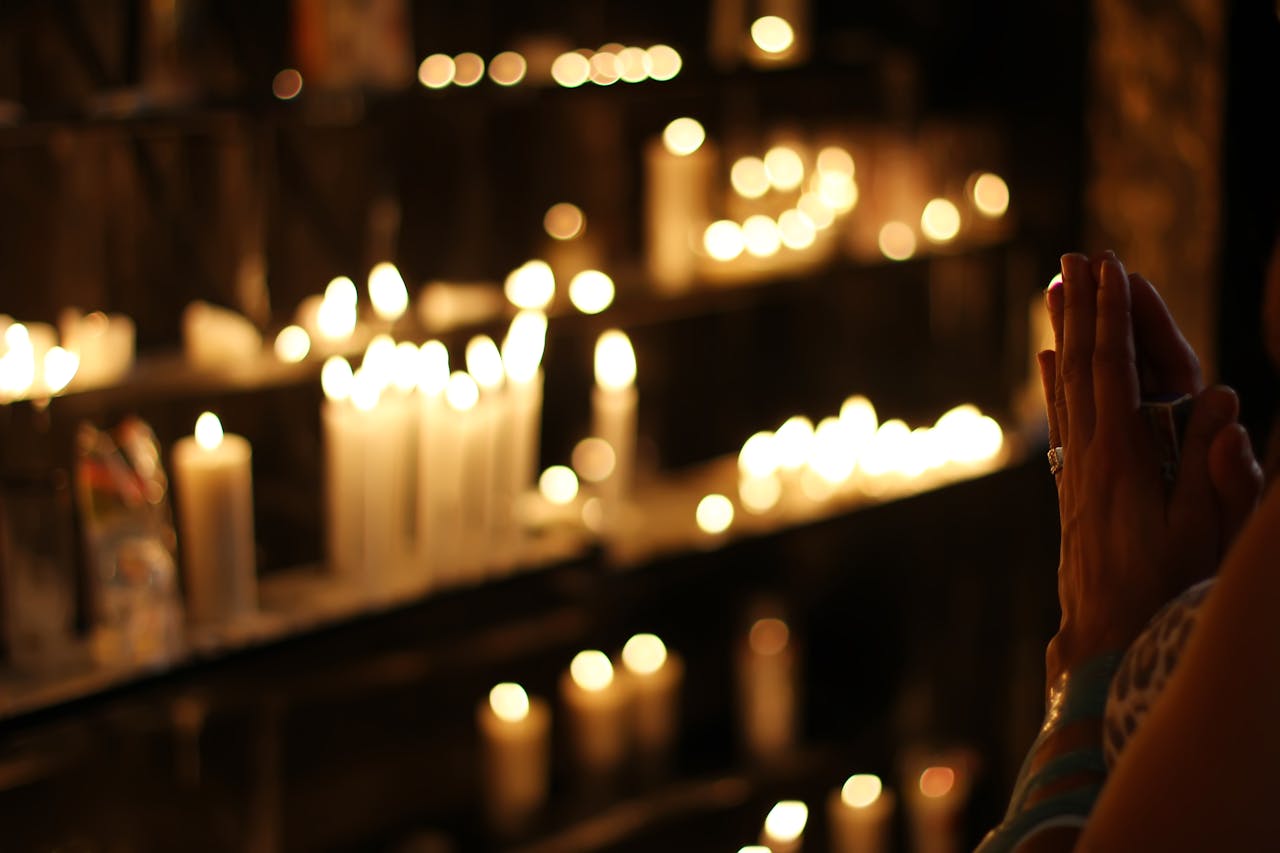 Person Praying in Front Lined Candles - Rodolfo Clix via Pexels